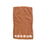 Beautiful hand-dyed itajime hemp moon linen hand towel in golden brown with undyed circles by kamppinen laid flat