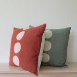 Hand dyed itajime kamppinen moon rust and sage green throw pillows with 5 undyed circles down middle on bench